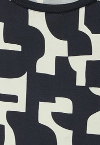 Svart och krämfärgad mönstrad tyg med abstrakta former; mjuk textur, rund halsringning och synlig sömdetaljering vid kragen.