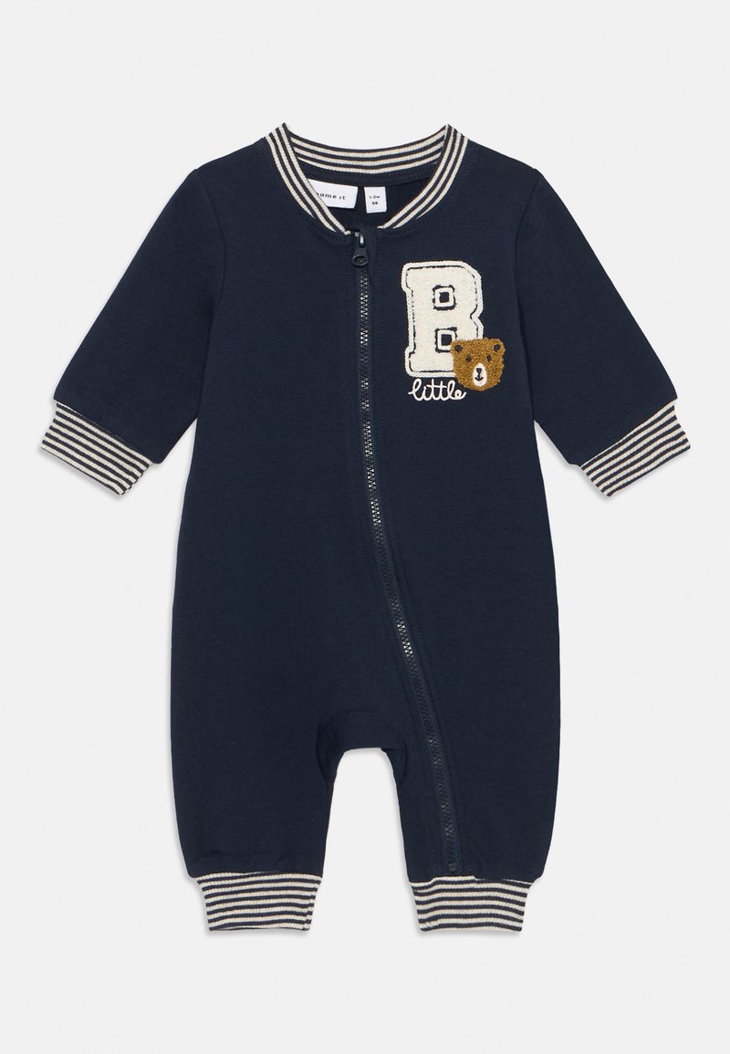 Dunkelblauer Reißverschluss-Overall mit gestreiften Bündchen, versehen mit einem gestickten Buchstaben "B" und einem Bärendesign. Aus weichem Baumwollmaterial.
