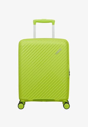 Bright green hard-shell suitcase with diagonal ridges, four spinner wheels, telescopic handle, and "American Tourister" logo.