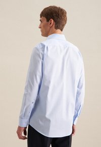 Camicia azzurra a maniche lunghe con colletto button-down, texture liscia e bottoni bianchi a contrasto ai polsini.
