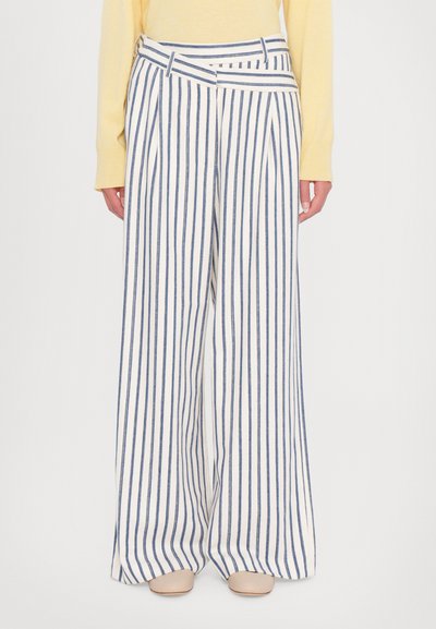 Wide-leg trousers in white and navy vertical stripes, featuring a high waist, pleats, and a textured fabric. Paired with a light yellow top.