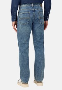 Šviesiai mėlyni džinsai su tiesiu sijonu, matomomis siūlėmis ir dviem užpakalinėmis kišenėmis. Juosmens juosta turi šviesiai rudo odos ženkliuką.