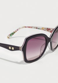 Occhiali da sole a forma di cat-eye di colore viola con una finitura lucida, dotati di decorazioni in oro e bacchette trasparenti con motivo.