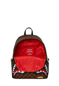 Zaino a scacchi marrone con interno rosso, caratterizzato da un design di bocca di squalo sulla parte anteriore. Accentuato con cerniera nera e hardware dorato. Edizione limitata.