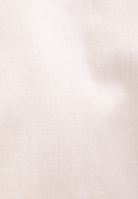 Jasnobeżowa tkanina lniana o gładkiej fakturze i subtelnym wzorze splotu. Powierzchnia wydaje się miękka i nieozdobiona.