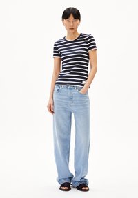 Camiseta de rayas azul marino y blanca de manga corta combinada con vaqueros de pierna ancha de color azul claro y sandalias negras de punta abierta. Diseño sencillo y corte relajado.