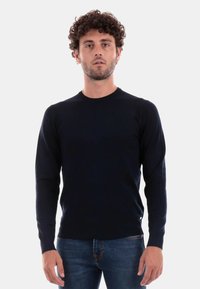 Maglione aderente a maniche lunghe di colore blu navy. Realizzato in un tessuto a maglia liscio, presenta un colletto rotondo e un discreto dettaglio con etichetta sull'orlo.