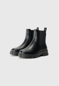 Sorte skinn ankle støvler med elastiske sidepaneler, forsterket hæltabu og chunky gummisåle med dype mønstre for godt grep.