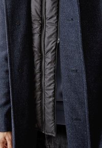 Cappotto navy con esterno in lana texturata, dotato di interno imbottito nero e chiusura con zip, tasche laterali e dettagli con bottoni.