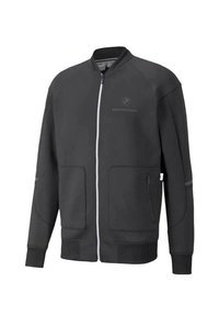 Chaqueta negra con cremallera y cuello y puños acanalados, que presenta dos bolsillos frontales y un pequeño logo en el pecho. Textura de tela suave.