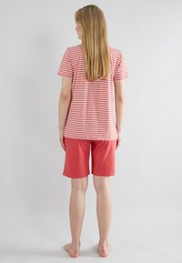 T-shirt à manches courtes rayé rouge et blanc associé à un short rouge uni, en coton, coupe décontractée, texture lisse.