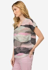 Blusa a V in tessuto leggero, con motivi ondulati in tonalità di grigio, rosa e verde. Maniche corte con una vestibilità rilassata.