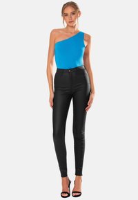 Blå bodysuit med en axel, kombinerad med svarta högmidjade skinny jeans. Slät textur, åtsittande design, fulländad med svarta klacksandaler.