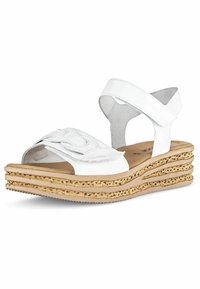 Sandale blanche en cuir avec une large sangle et une sangle de cheville ajustable. Présente une semelle en liège multi-couches avec des détails texturés.