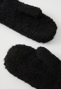 Moufles noires en matériau doux, texturé et pelucheux, avec une forme arrondie et une apparence tridimensionnelle. Aucun matériel ou motif visible.