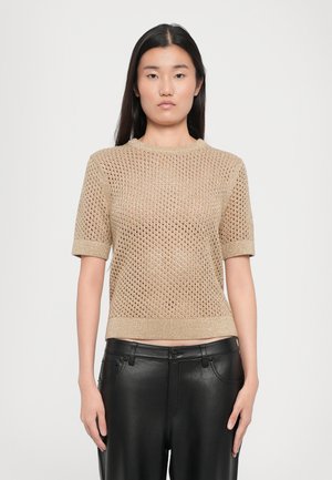 Kurze Ärmel, Rundhalsstrickoberteil in Gold mit offener Strickmuster. Kombiniert mit schwarzen Lederhosen. Strukturiert, leichtes Material.