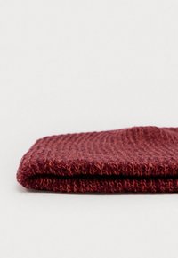 Pletená čiapka v tmavo červenej farbe s textúrovaným, rebrovaným vzorom. Sklopená na okraji, ukazuje mäkkú, teplú látku vhodnú do chladného počasia.
