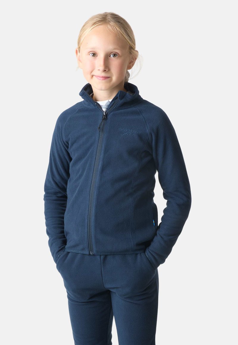 Granatowa polarowa kurtka na zamek z wysokim kołnierzem i bocznymi kieszeniami, w zestawie z pasującymi spodniami polarowymi. Gładka textura, dyskretna marka.