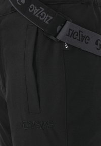 Zwarte joggerbroek met een gladde textuur, voorzien van zijzakken en een geborduurd "ZIGZAG" logo. Verstelbare band met logo-detail.