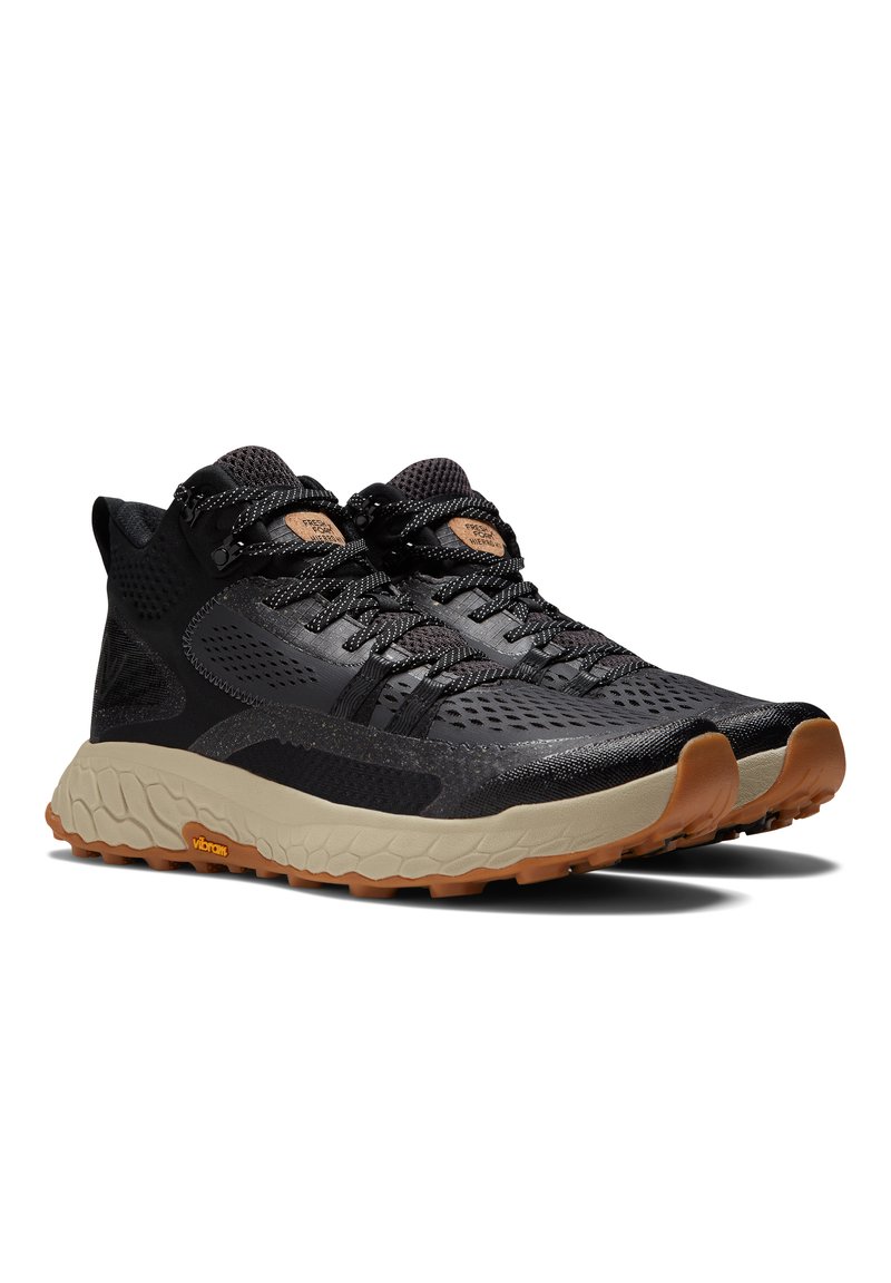 Zwarte sportieve schoenen met een bovenwerk van mesh, contrasterende rubberen zool en textuuraccenten. Bevat een gegraveerd logo en gemusterde veters.