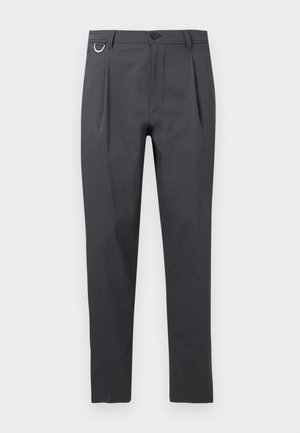 Dunkelgraue schmal geschnittene Hose mit vorderen Falten, Gürtelschlaufen, Knopfverschluss und einem kleinen Metallring auf der linken Seite.