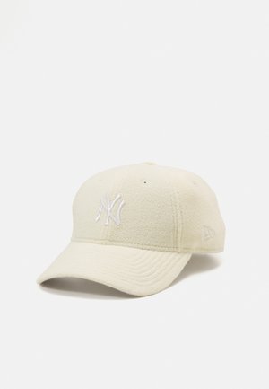Gorra de los New York Yankees en forro polar color blanco roto. Presenta un logo bordado en la parte frontal, visera curva y acentos cosidos. Textura suave, diseño de seis paneles.