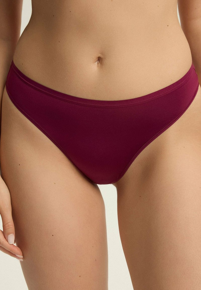 Bordowy dół bikini wykonany z miękkiego materiału, o niskim kroju i gładkich brzegach, bez dodatkowych wzorów czy detali metalowych.
