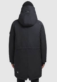 Parka aislante negra con capucha, detalles de botones y una etiqueta con el logo en el dobladillo inferior. Presenta una textura lisa y elegante y un diseño hasta la altura de la rodilla.