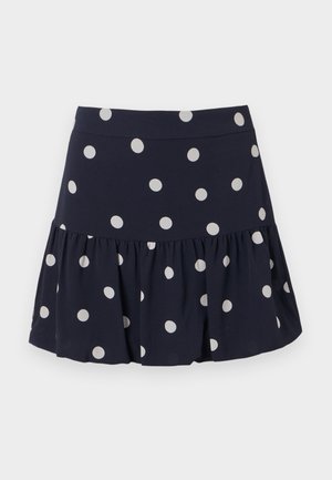 Navy blue skater skirt made from lightweight fabric with a flared hem. Features large white polka dots and an elastic waistband.