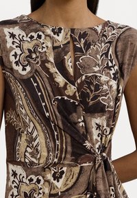 Braunes Kleid mit Blumenmuster, das einen Schlüssel-Ausschnitt, kurze Ärmel und eine gebundene Taille aufweist, gefertigt aus weichem, strukturiertem Stoff.