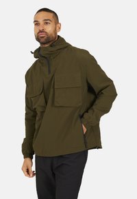 Olijfgroen pulloverjack met twee grote voorzakken, verstelbare capuchon en elastische manchetten, gemaakt van vochtregulerende stof.