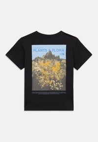 Μαύρο T-shirt με γραφικό άλμπουμ με βουνά της κοιλάδας Yosemite και φυτά, φόντο με γαλάζιο ουρανό, και κείμενο «PLANTS & FLORA» μαζί με το λογότυπο The North Face.
