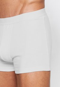 Fehér pamut boxer alsónadrág, puha elasztikus derékpánttal. Egyszerű dizájn, testhezálló fazon és sima textúra, mindennapi viseletre alkalmas.