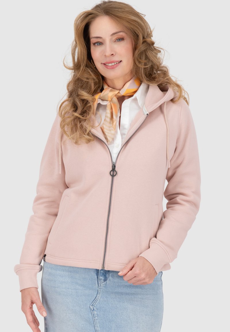 Felpa con zip di colore rosa chiaro, dotata di cappuccio, con zip argentata, tasche laterali, polsini a costine, abbinata a una maglietta bianca e una sciarpa fantasia.
