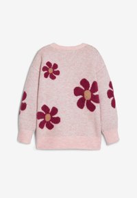 Strickpullover in lichtrosa mit übergroßen Blumenmustern in Burgundy und goldenen Akzenten; weicher Textur, runder Ausschnitt und lange Ärmel.