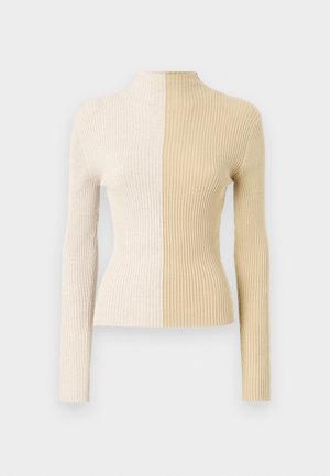 Rebrast pulover s turtleneck-om in dolgimi rokavi, v dveh barvah, krem in bež, ki poudarja kontrastne teksture in barve.