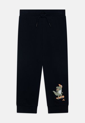 Pantalon de survêtement bleu marine pour tout-petit avec taille et poignets élastiques, avec un dinosaure vert portant une casquette et faisant du skateboard près de la cheville droite.