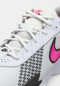 Nike sneakers med en hvid mesh-overdel, sorte accenter, pink swoosh, houndstooth-mønster og grå gummisål. Snørebåndsdesign med synlige syninger.