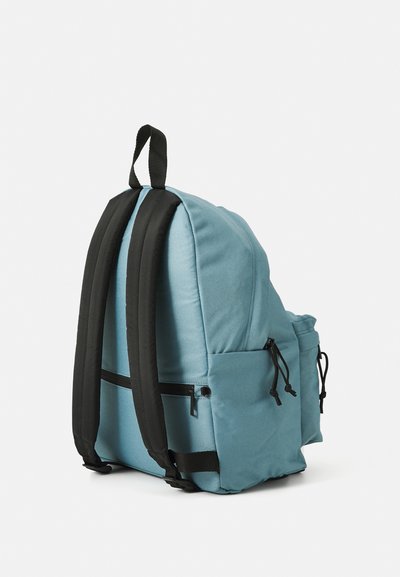 Un sac à dos en tissu bleu avec des bretelles rembourrées noires, des poches latérales et une poche zippée à l'avant. Il dispose d'une poignée supérieure pour un transport facile.