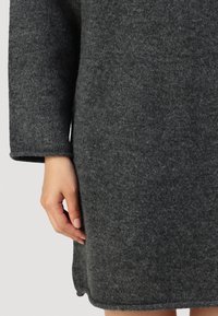 Grå ullkjole med rett snitt, lange ermer ogsøm som ender rett over kneet; har en myk tekstur.