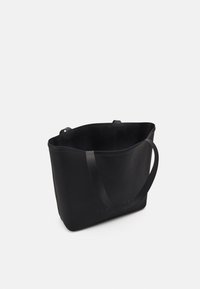 Grand sac fourre-tout noir avec deux poignées, légèrement ouvert en haut, et texte de marque subtil sur une surface lisse sur fond blanc.