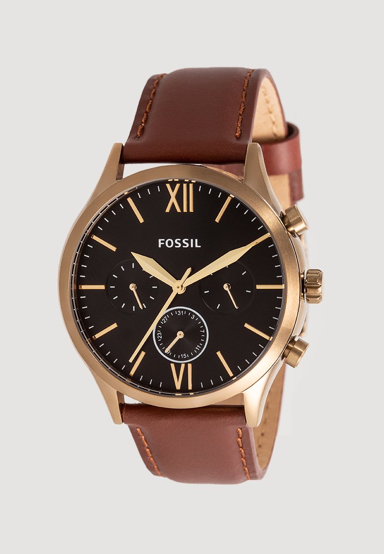 Reloj con correa de cuero marrón, esfera negra, marcadores en tono dorado y tres subesferas. Presenta los números romanos XII y VI. Marca: Fossil.