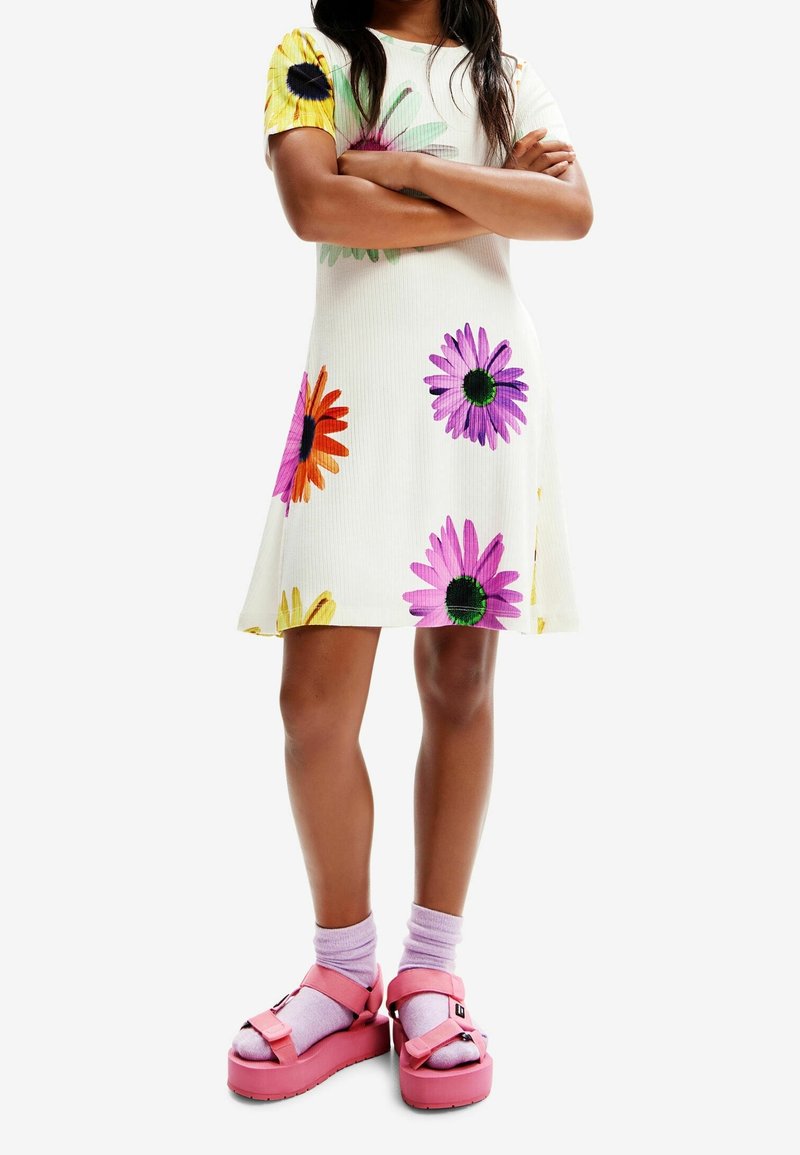 Abito bianco a maniche corte con motivi floreali multicolori. Abbinato a sandali platform rosa e calzini lilla.