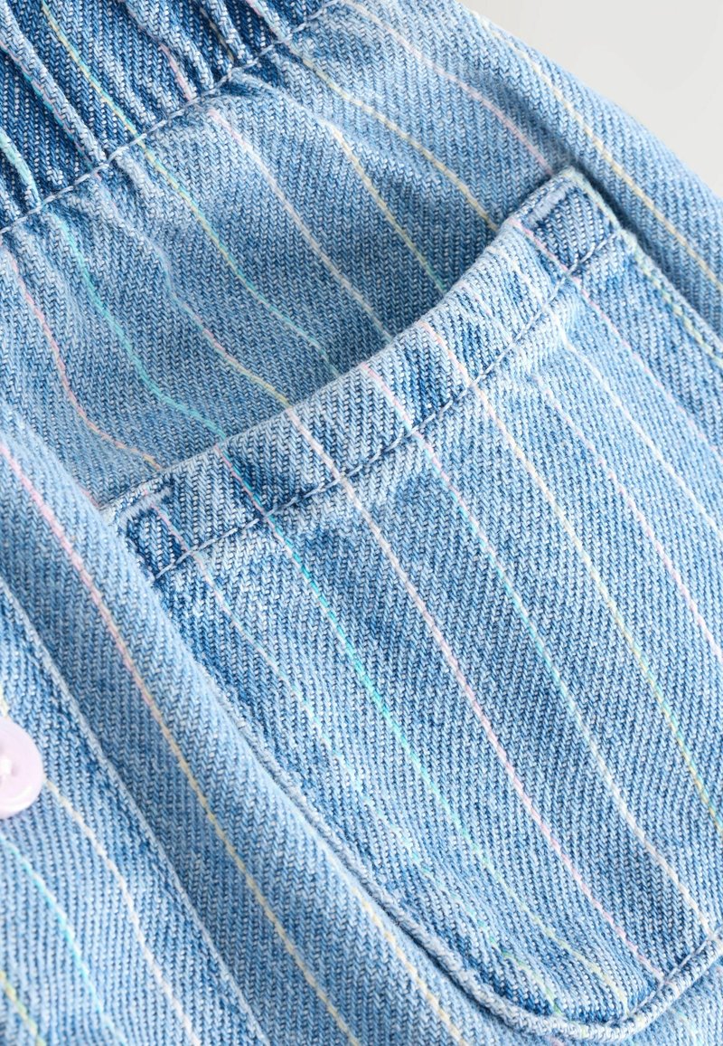Tissu bleu clair avec de fines rayures verticales pastel et une poche carrée aux bords cousus.
