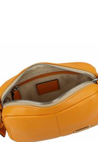 Borsa con cerniera in vivace pelle arancione con una texture liscia. Presenta una fodera interna beige e una piccola tasca interna.