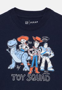 Μπλε ναυτικό μπλουζάκι με χαρακτήρες κινουμένων σχεδίων: Ρεξ, Τζέσι, Γούντι και Μπαζ Λάιτγιρ, με το κείμενο «TOY SQUAD» σε λευκό από κάτω.