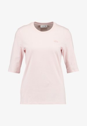 Lichtroze T-shirt met korte mouwen, gemaakt van zachte katoen, met een ronde hals en het Lacoste-logo geborduurd op de borst.