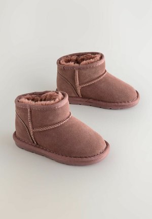 Lühikesed roosa suede saapad, millel on pehme vooder ja õmmeldud detailsed, ümarate varvastega ning lame kummitald.
