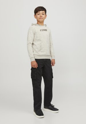 Hellgrauer Hoodie mit "CORE" auf der Vorderseite, kombiniert mit dunklen Cargo-Hosen und schwarzen Schuhen. Lässige Passform mit einer Fronttasche.