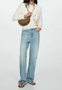 Witte getextureerde jas met zilveren knopen, crèmekleurige top, lichtblauwe wijde jeans en een bruine schoudertas. Zwarte slippers maken de look compleet.